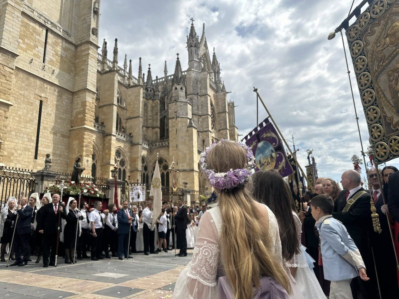 Multitudinaria procesión del Corpus Christi en León con participantes y banderas.