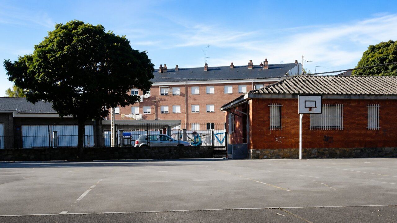 Patio del CEIP San Andrés-La Borreca con canasta de baloncesto y edificios al fondo