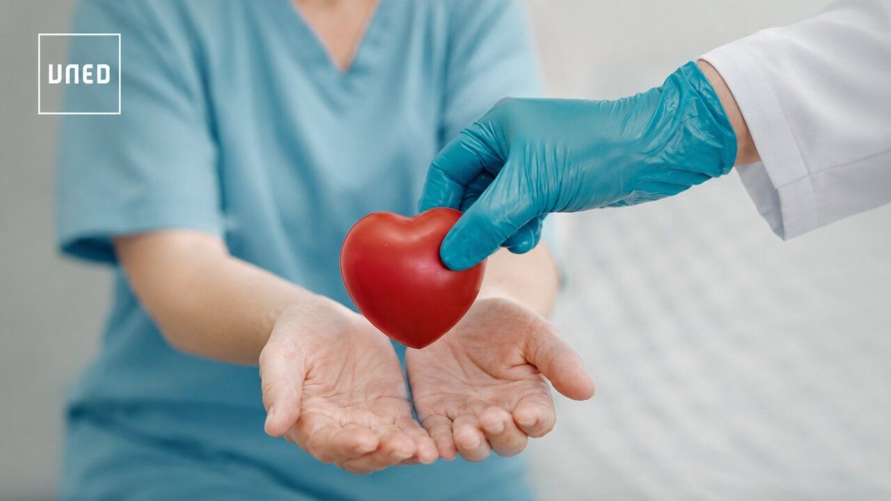 Mano entregando un corazón de juguete a otra mano en un contexto médico