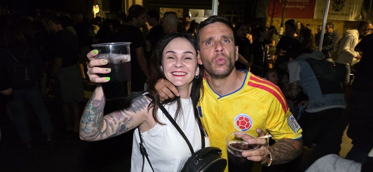 Pareja sonriente en festival, sosteniendo vasos de bebida