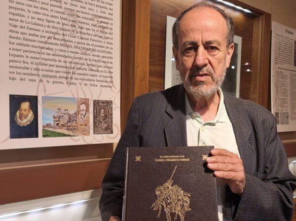 Hombre sosteniendo una edición de Don Quijote en una exposición