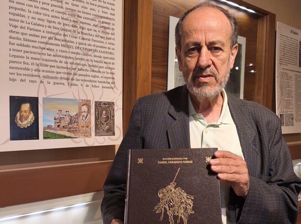 Hombre sosteniendo una edición de Don Quijote en una exposición