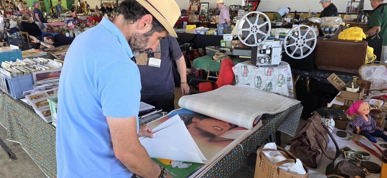 Persona revisando artículos en una feria de antigüedades y coleccionismo
