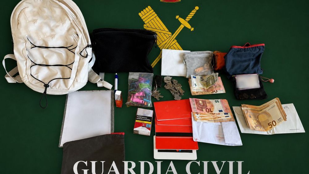 Mochila blanca con objetos y dinero en efectivo sobre fondo verde