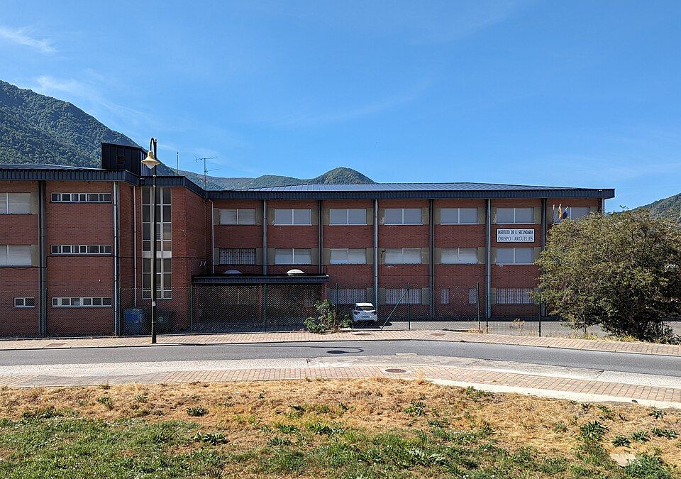 Fachada del IES Obispo Argüelles en Villablino, rodeado de montañas.