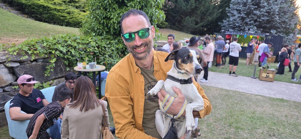 Hombre sonriente sosteniendo un perro en la inauguración de la terraza de verano.