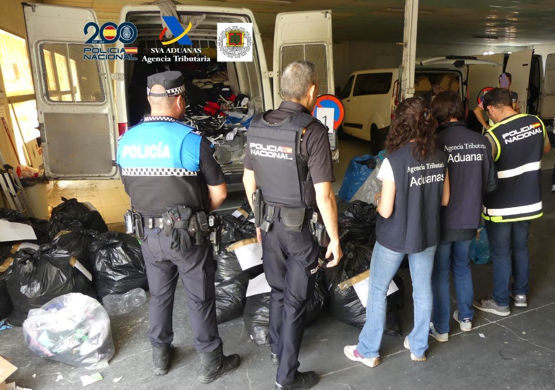 Agentes de policía revisando ropa falsificada en un mercadillo
