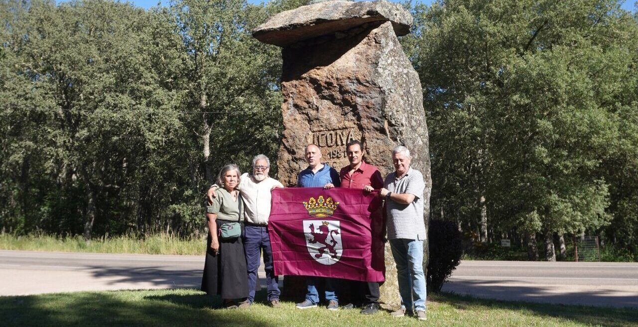 Grupo de personas sosteniendo una bandera en un monumento en Salamanca