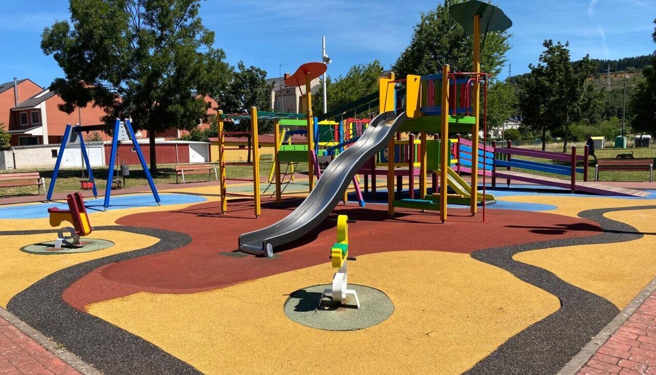 Parque infantil en Compostilla con tobogán y columpios coloridos