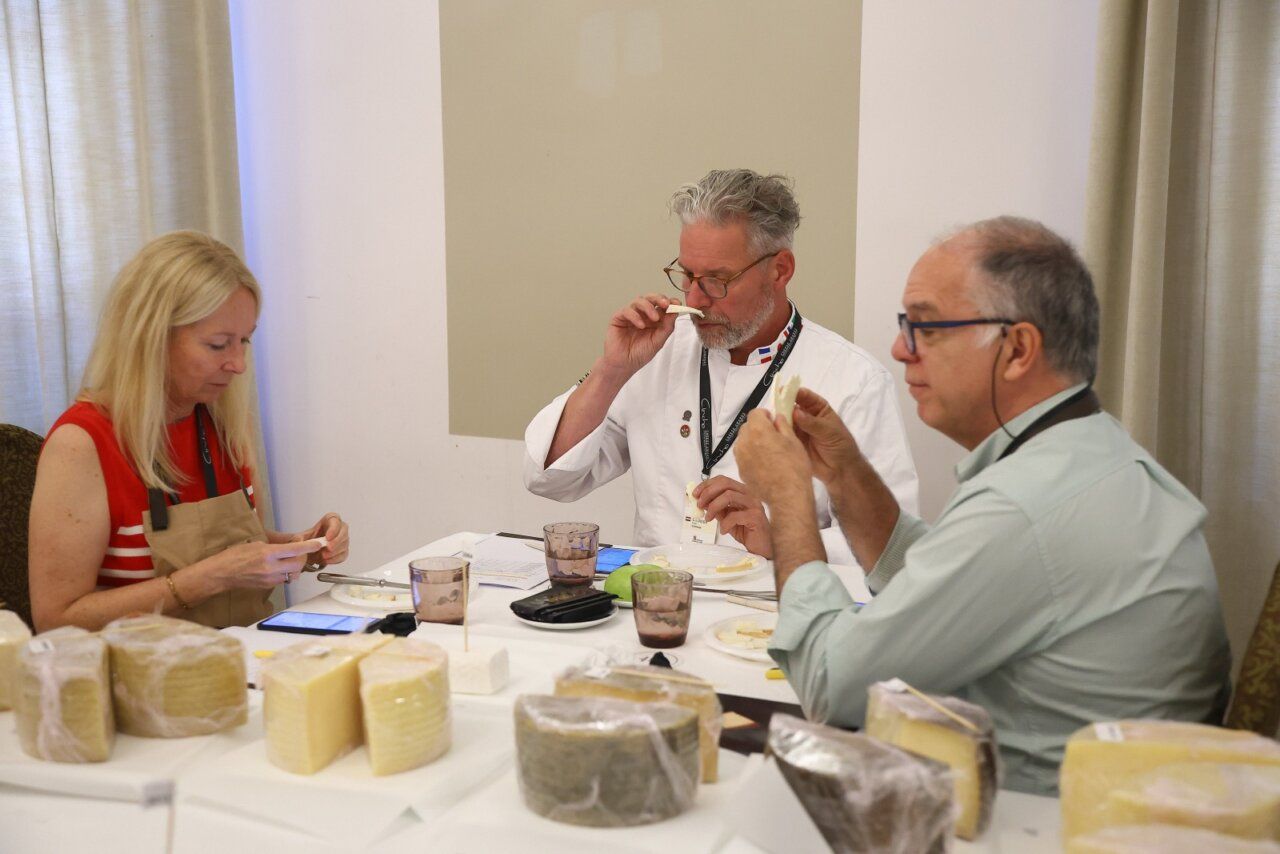 Tres personas degustando quesos en una mesa con varios tipos de queso.