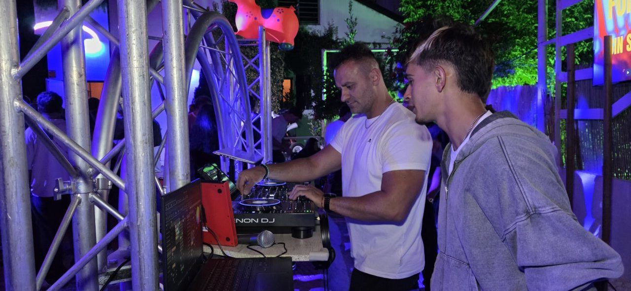Dos personas en una fiesta observando a un DJ en acción