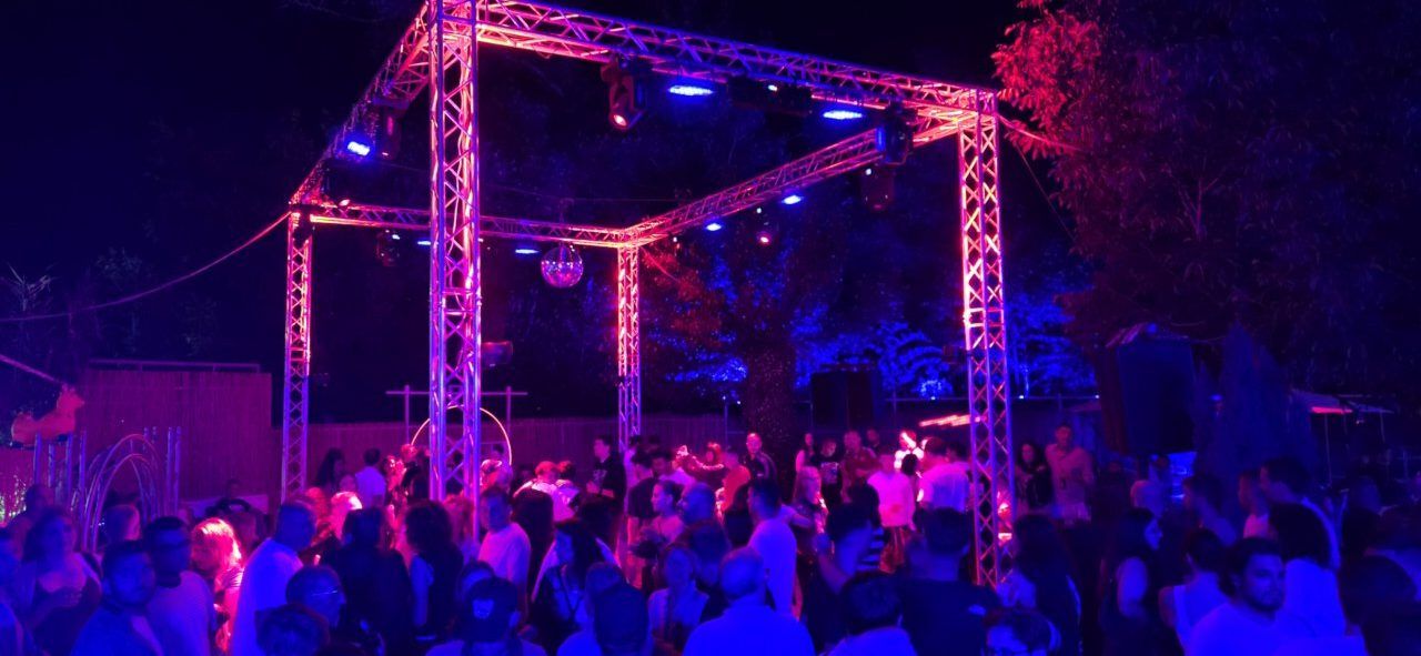 Fiesta nocturna en Vega de Espinareda con luces de colores y gente bailando.