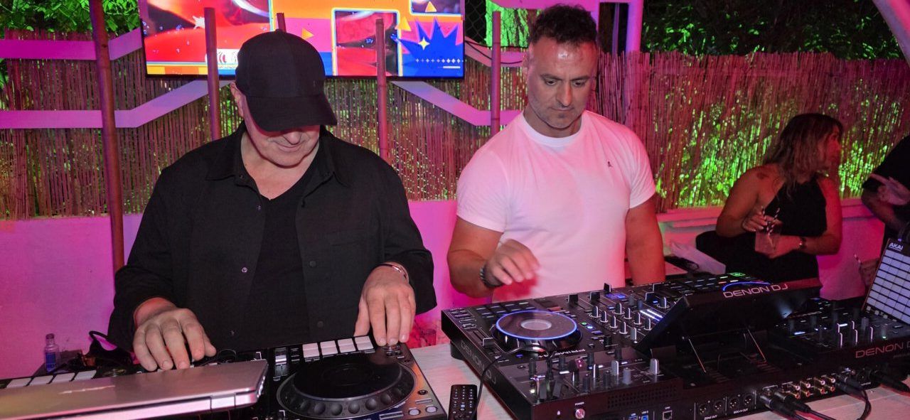 Dos DJs actuando en un evento nocturno con luces de colores