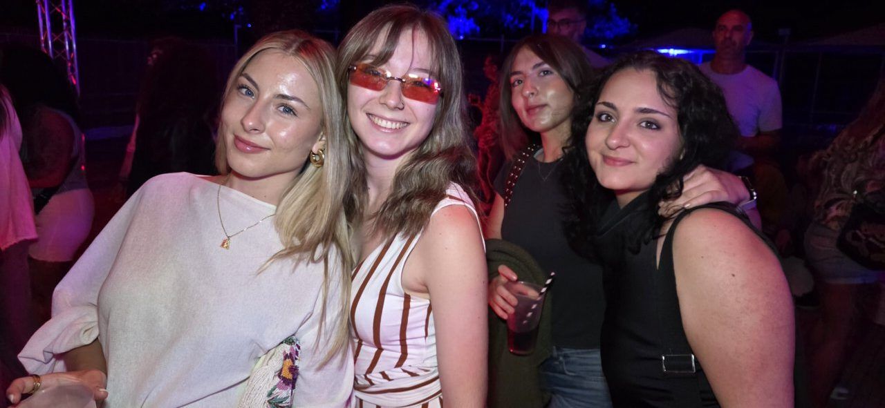 Grupo de amigas sonriendo en un evento nocturno con luces de colores