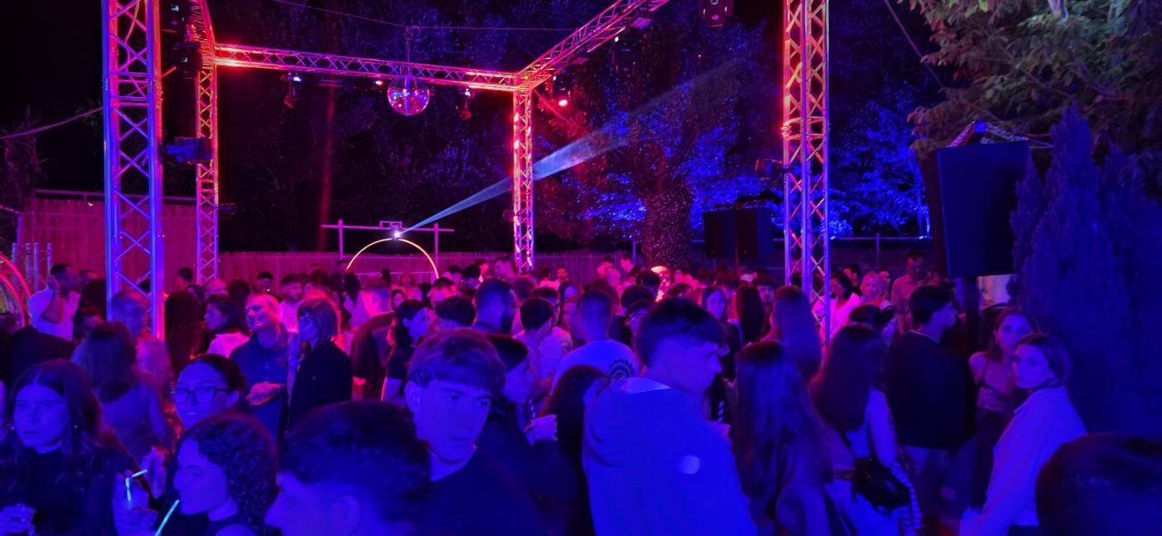 Multitud disfrutando de una fiesta nocturna con luces de colores