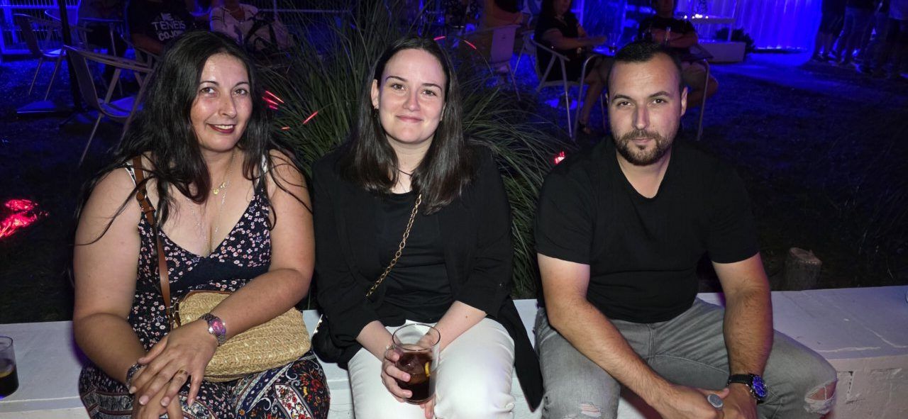 Tres personas sentadas en un evento nocturno con luces de colores