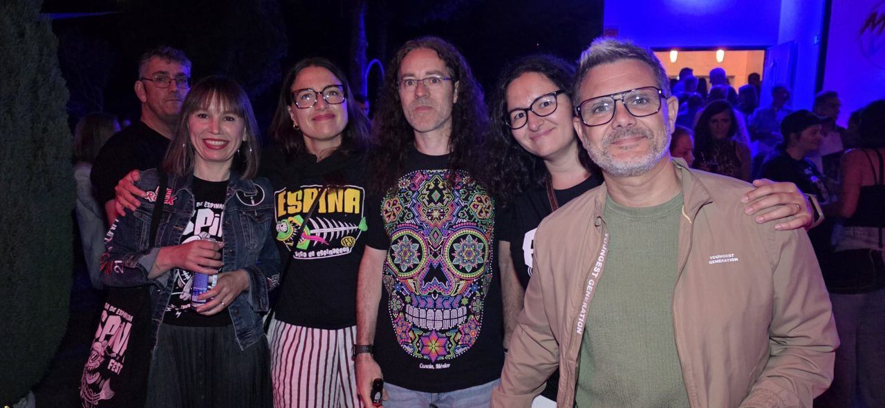 Grupo de personas posando en un evento nocturno con luces de fondo