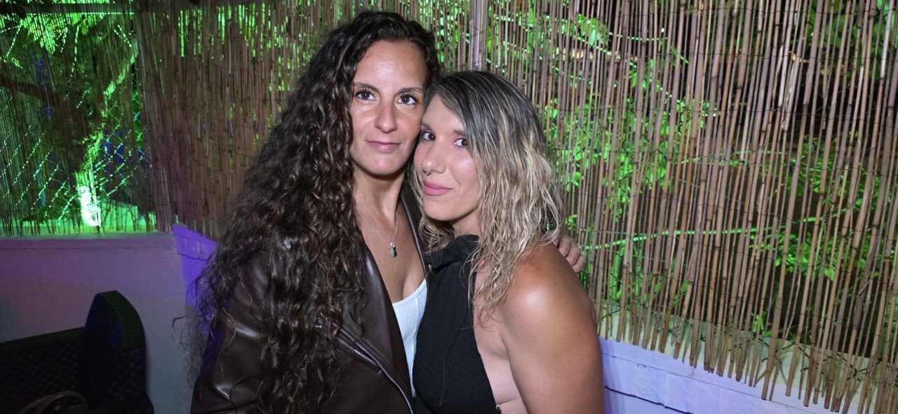 Dos mujeres posando juntas en un ambiente festivo con luces verdes