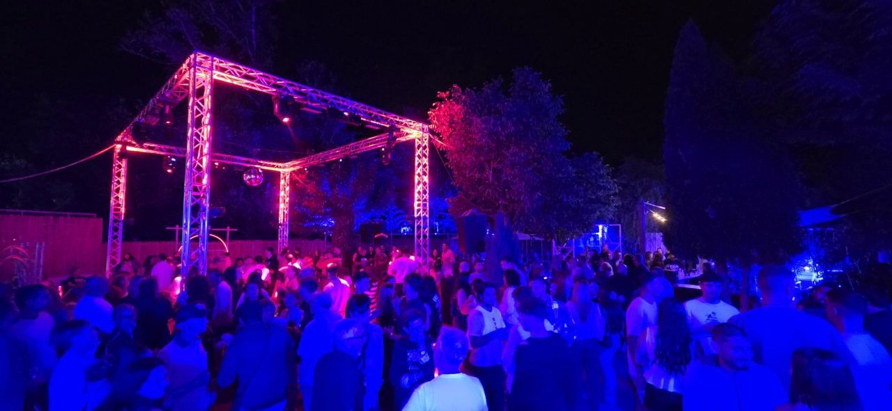 Fiesta nocturna con luces de colores y gran afluencia de personas.