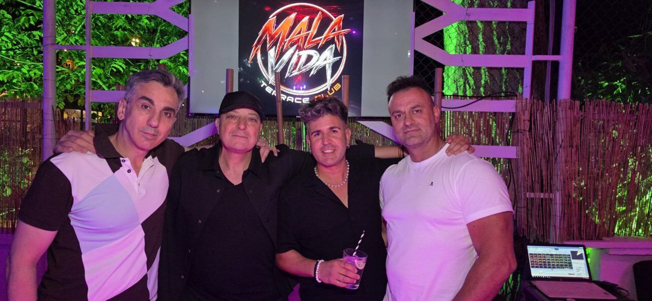 Cuatro hombres posando en un club con luces de colores
