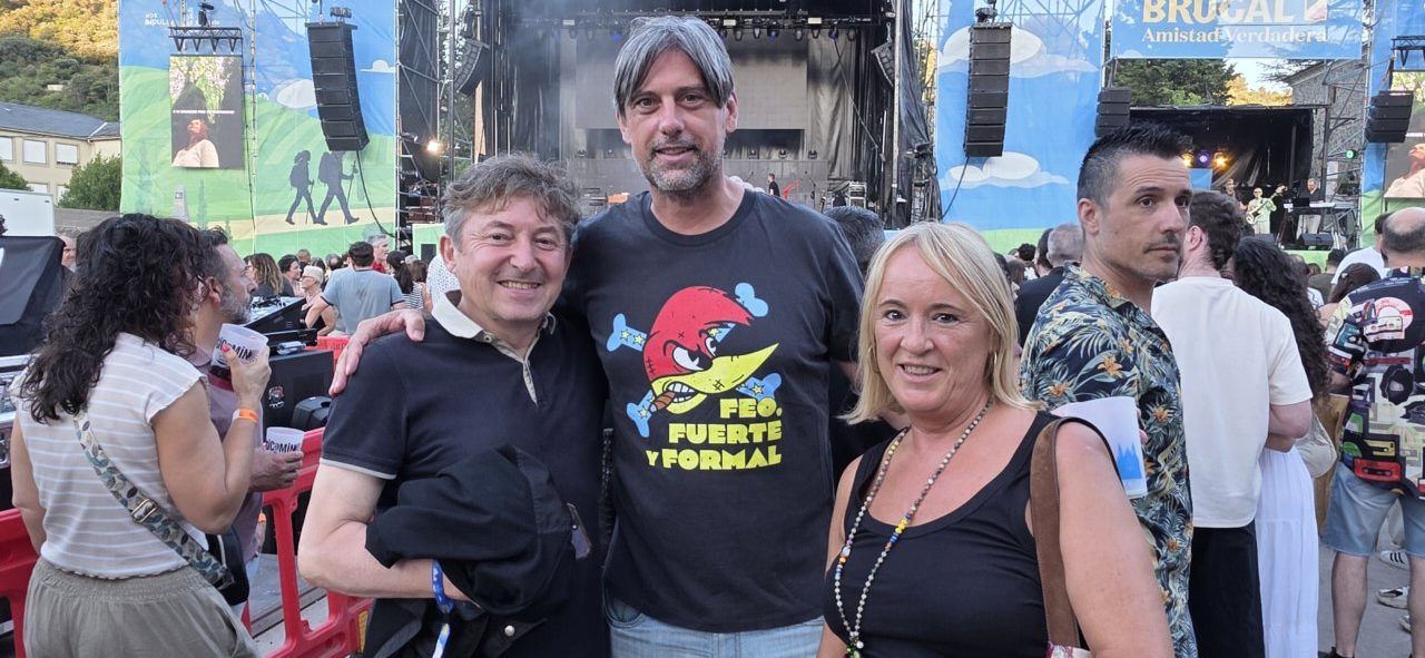 Tres personas posando en un concierto al aire libre con escenario