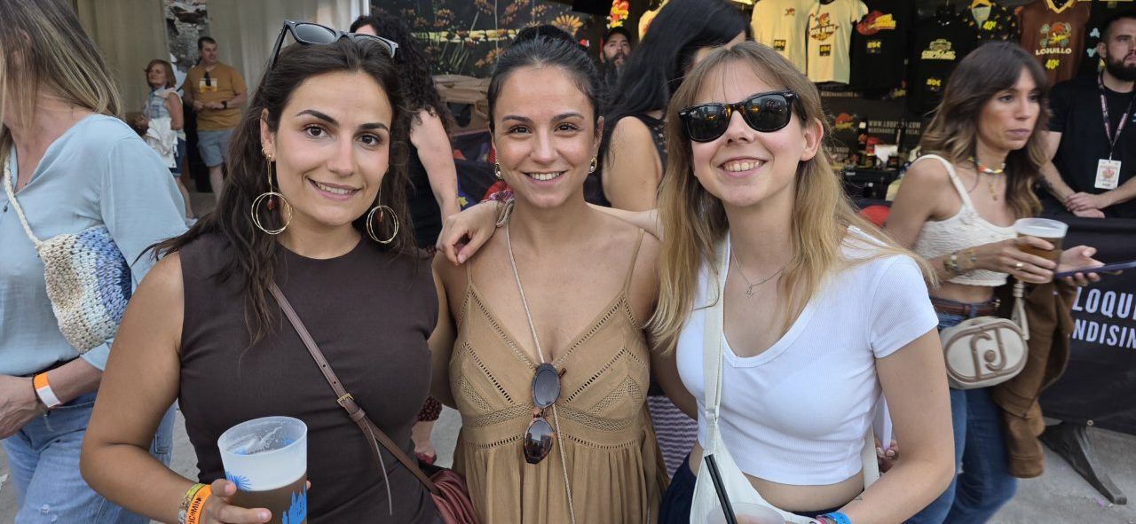 Tres amigas sonriendo en un festival de música al aire libre