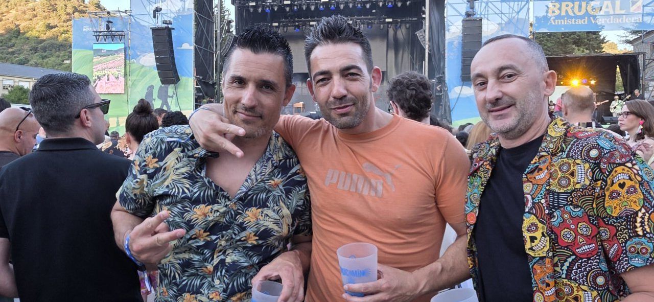 Tres hombres disfrutando de un concierto al aire libre en un festival de música
