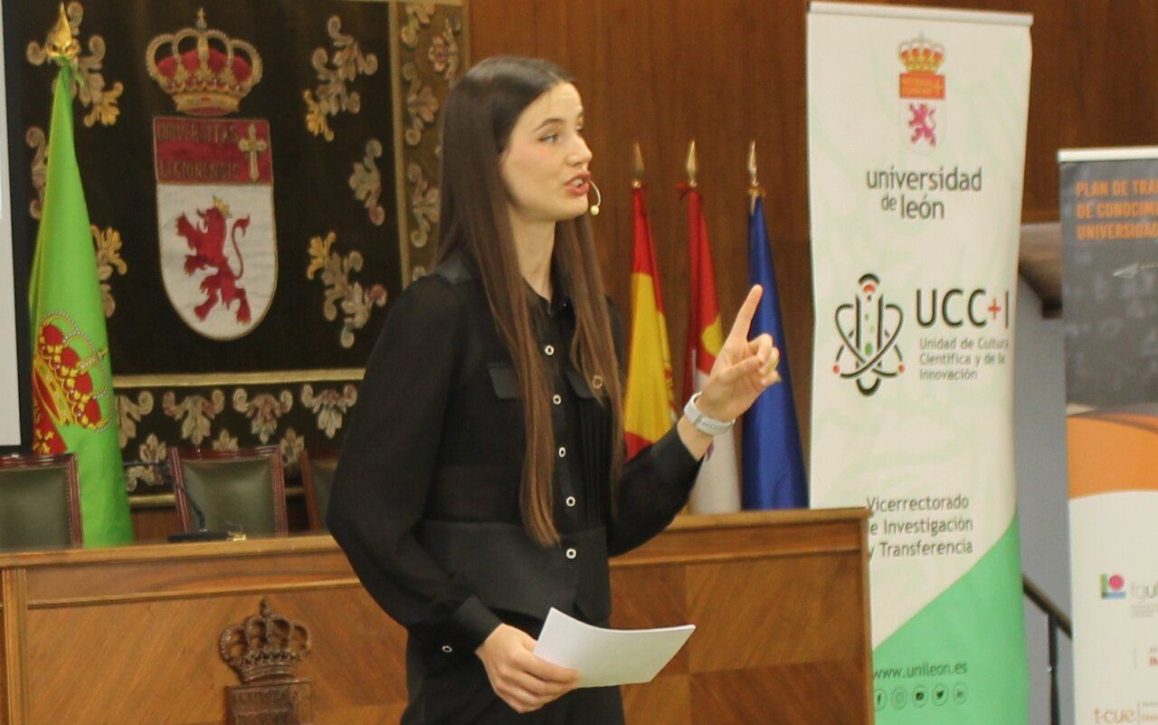 Mujer hablando en una conferencia con banderas de fondo