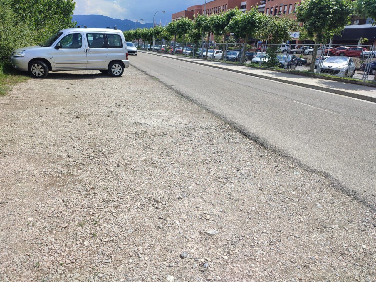 Vista de una calle en Ponferrada con un coche estacionado y terreno sin asfaltar