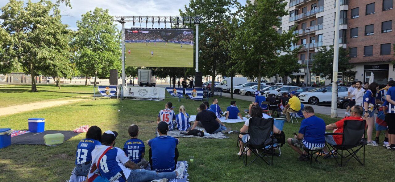 Aficionados de la SD Ponferradina viendo un partido en pantalla gigante al aire libre.