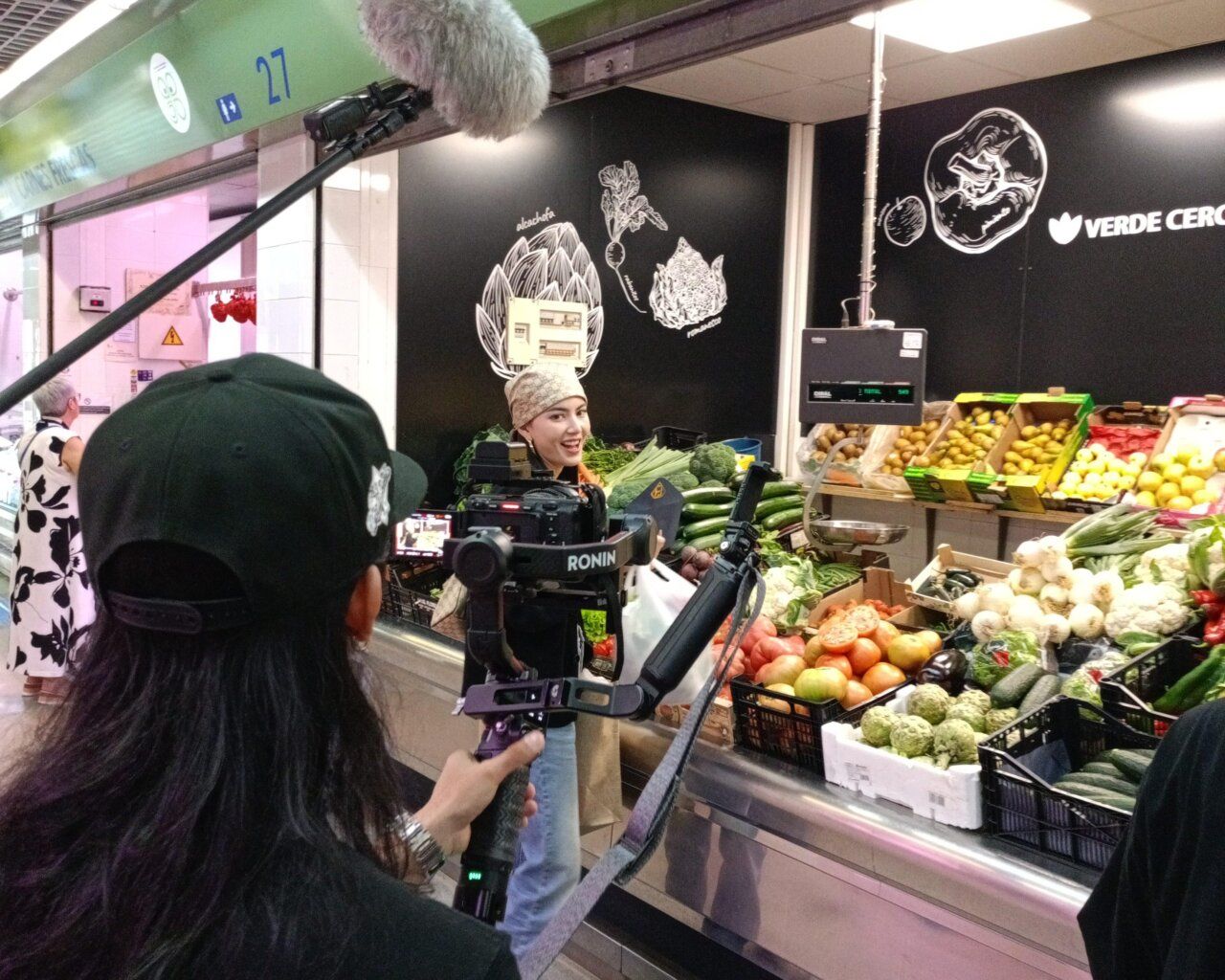Participante del reality en el Mercado de Abastos de Ponferrada con verduras frescas.