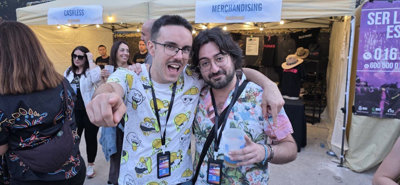 Dos amigos posando en un evento de música con camisetas coloridas