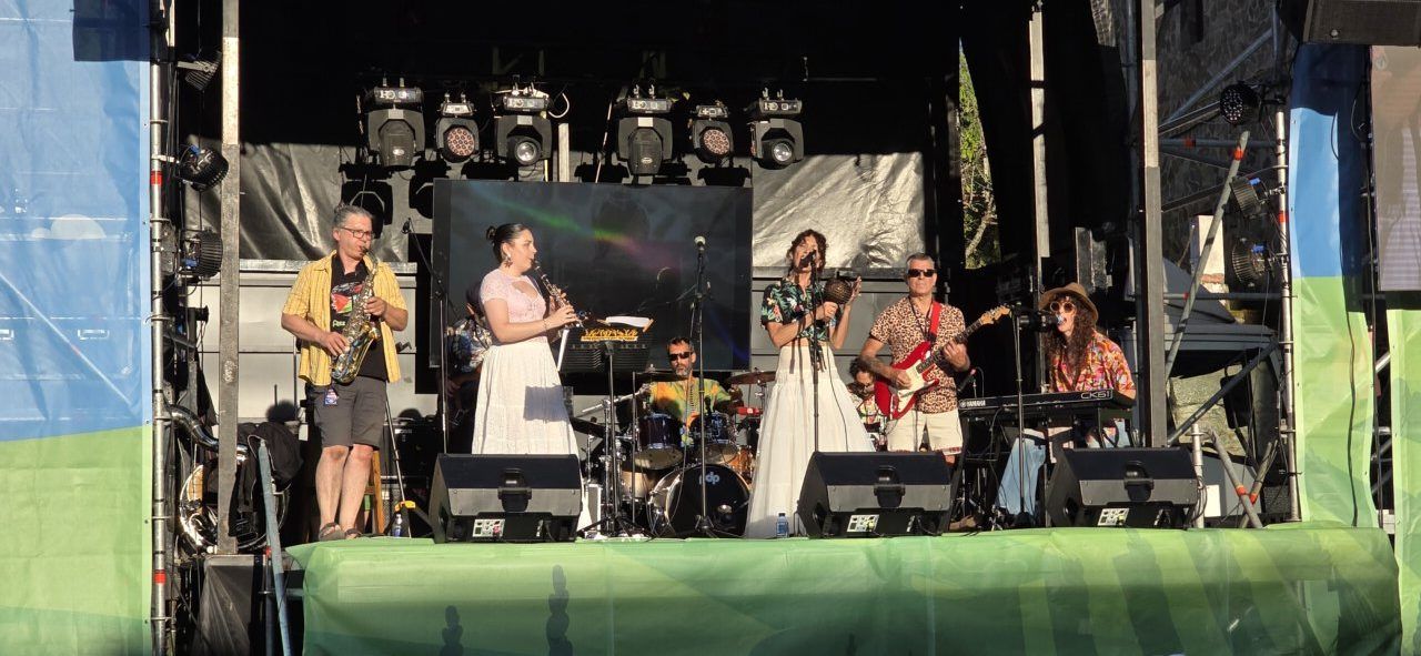 Banda tocando en un escenario al aire libre durante un evento musical