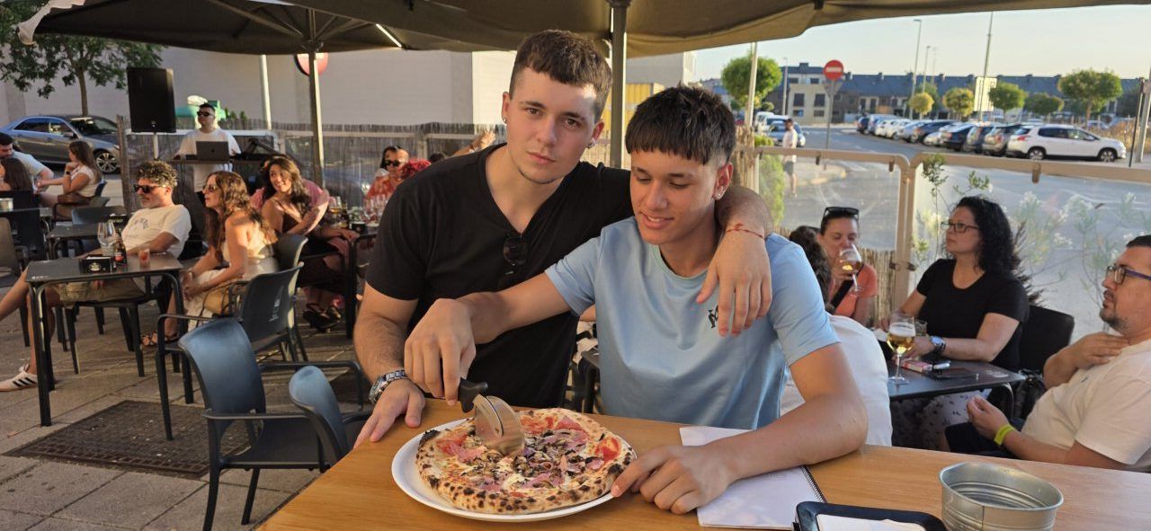 Dos jóvenes disfrutando de una pizza en la Pizzería Mama Mia durante su aniversario
