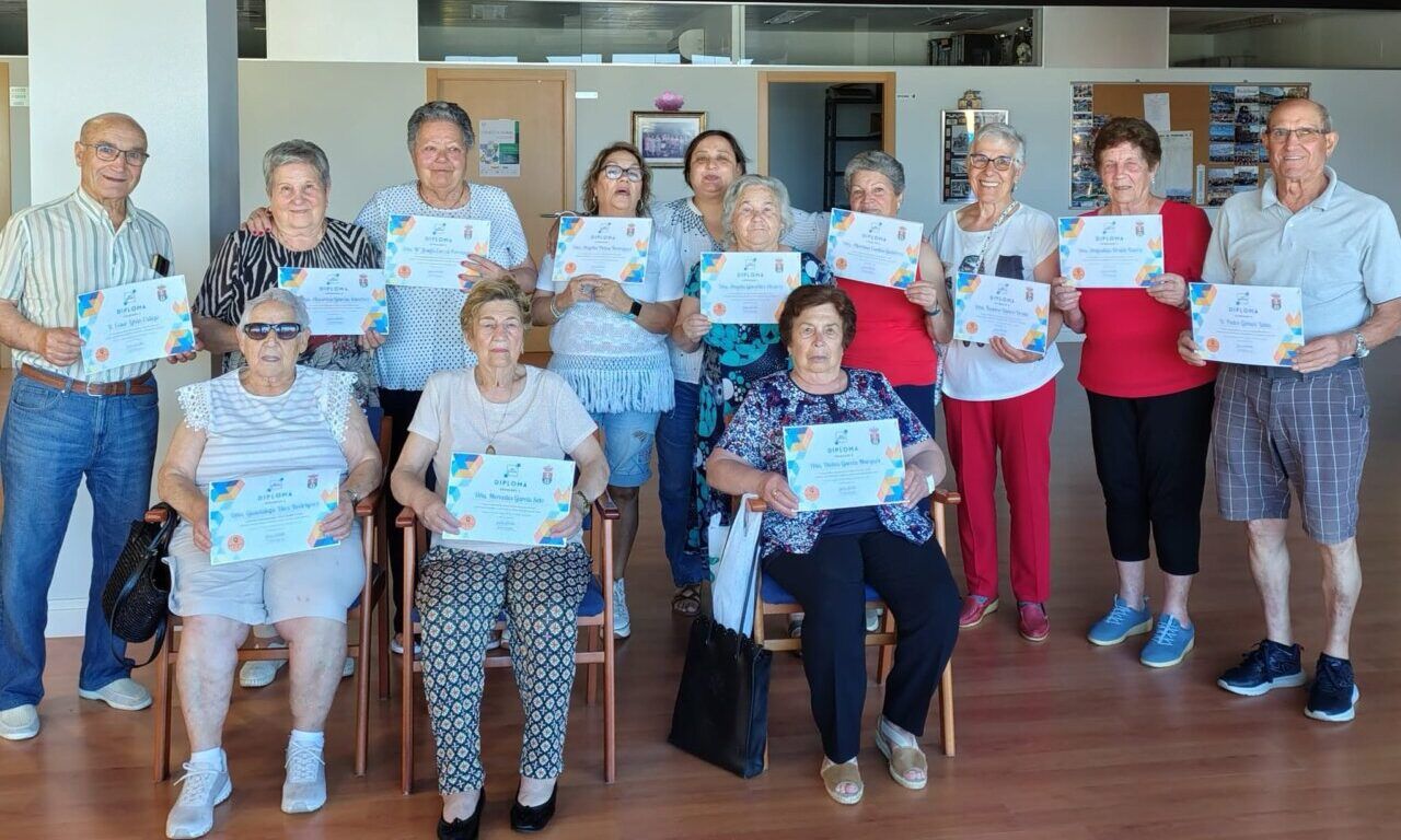 Grupo de personas mayores sosteniendo diplomas en un evento comunitario