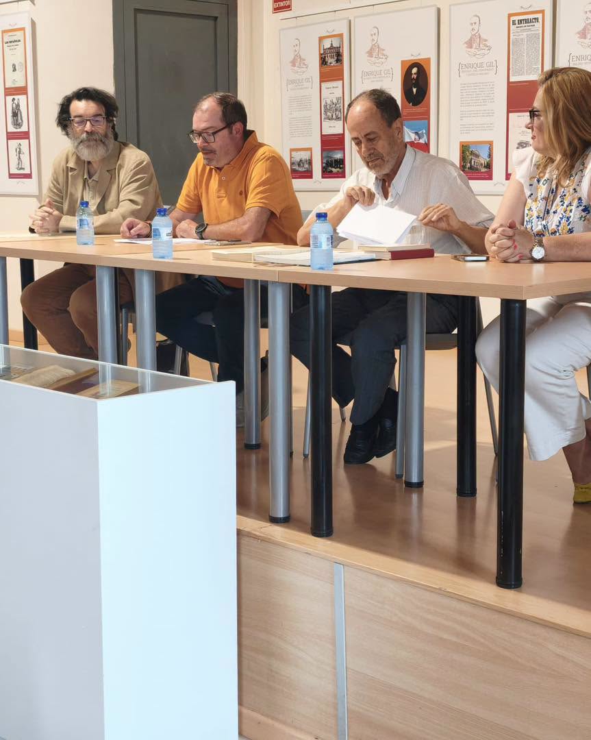 Cuatro personas sentadas en una mesa durante una exposición en Arganza.