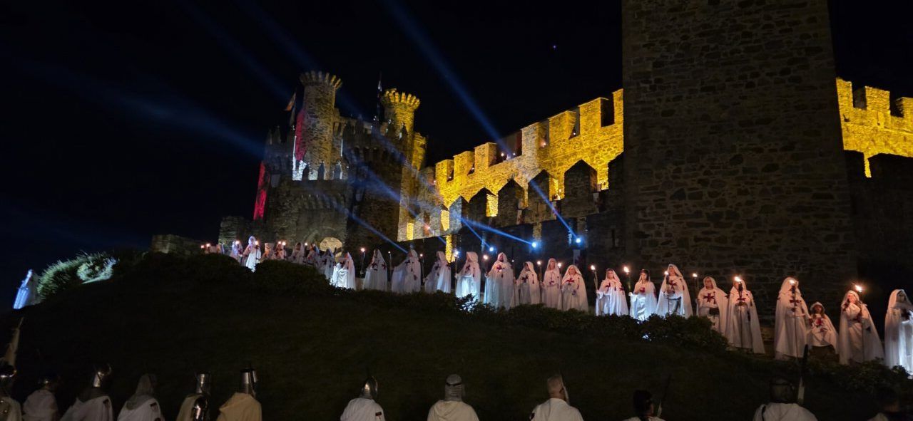 Desfile Templario con participantes vestidos de blanco en la noche