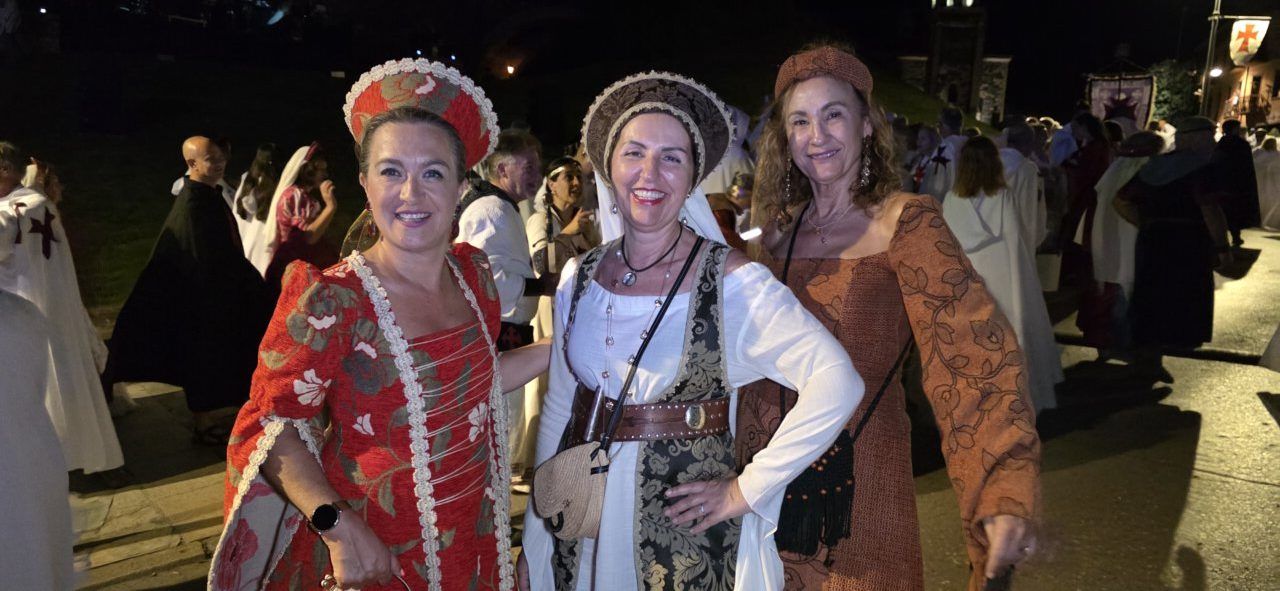 Tres mujeres vestidas con trajes medievales en un desfile templario