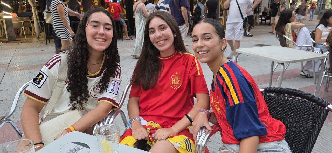Tres jóvenes aficionados animando a España en la Plaza Fernando Miranda