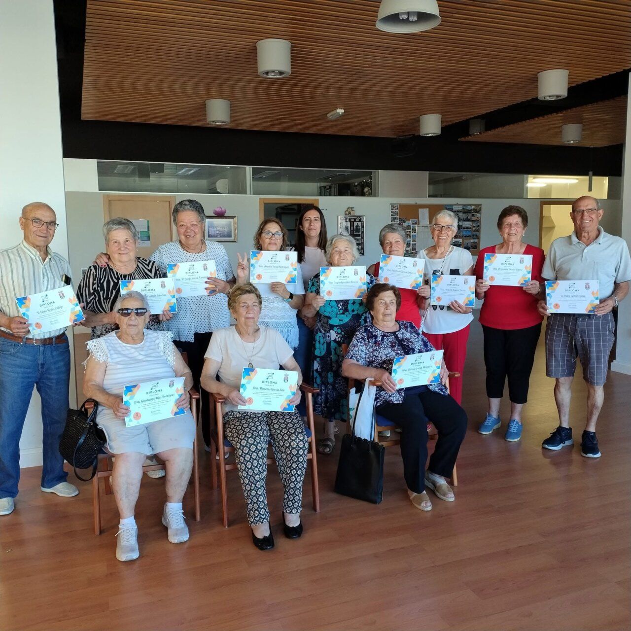 Grupo de personas mayores sosteniendo diplomas en un evento de clausura