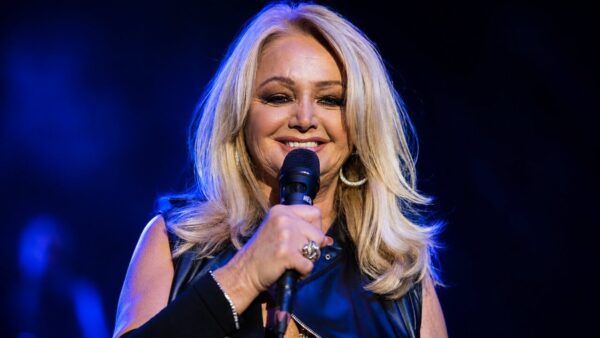 Bonnie Tyler sonriendo mientras sostiene un micrófono en un escenario