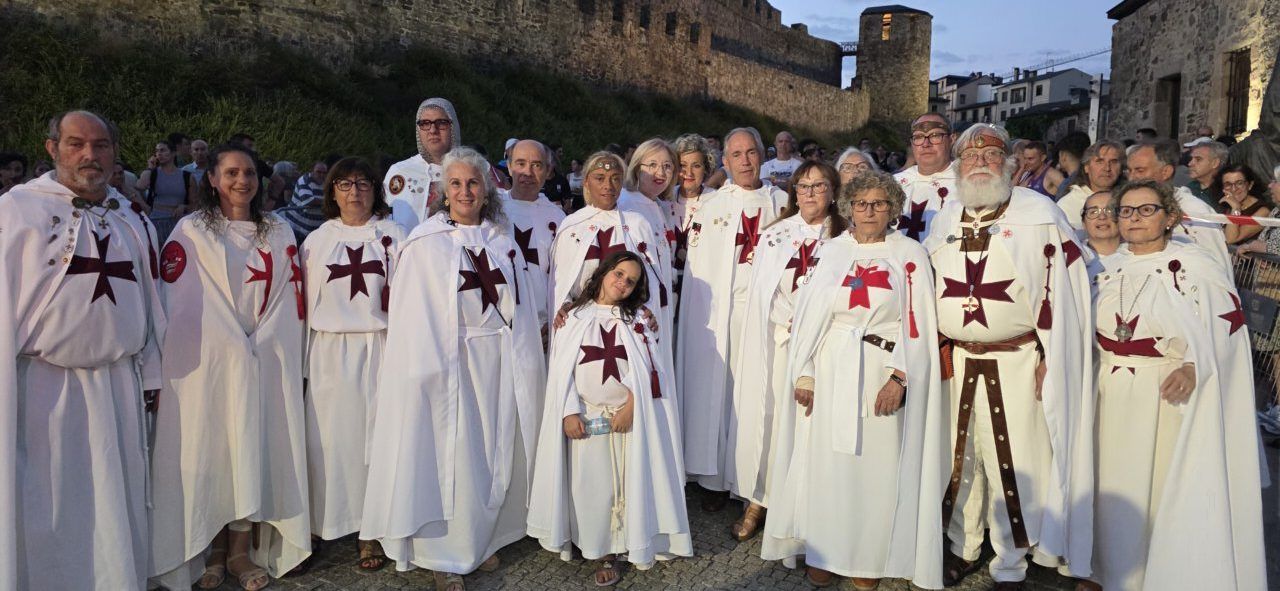 Grupo de participantes en la carrera nocturna vestidos con túnicas blancas y cruces rojas