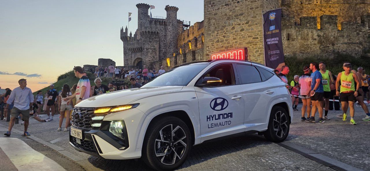 Corredores y un coche en la carrera nocturna junto al Castillo de los Templarios