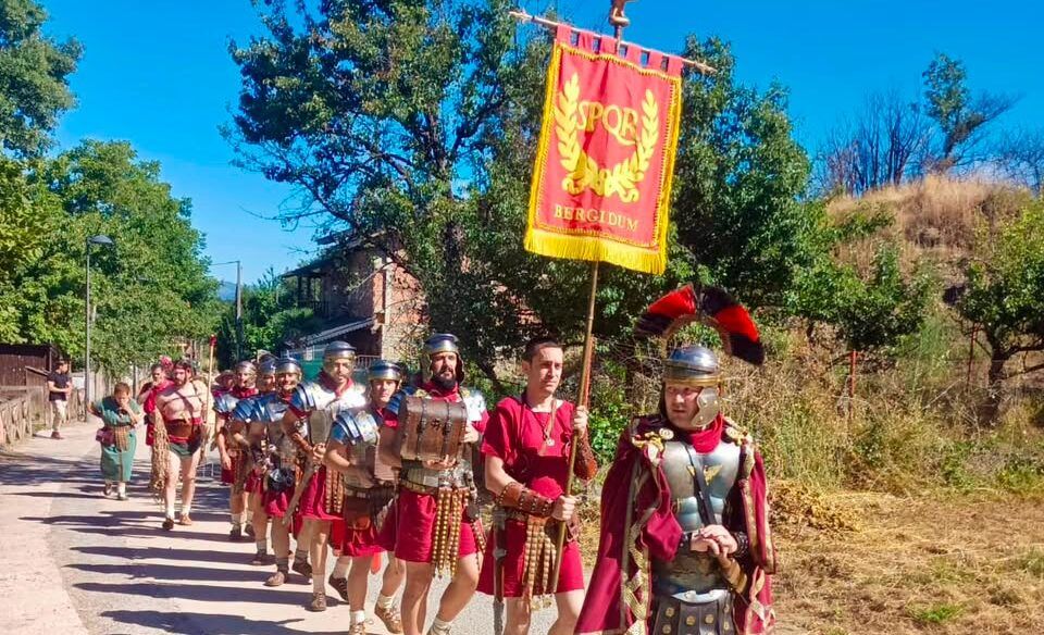 Grupo de personas vestidas como romanos en desfile con estandarte