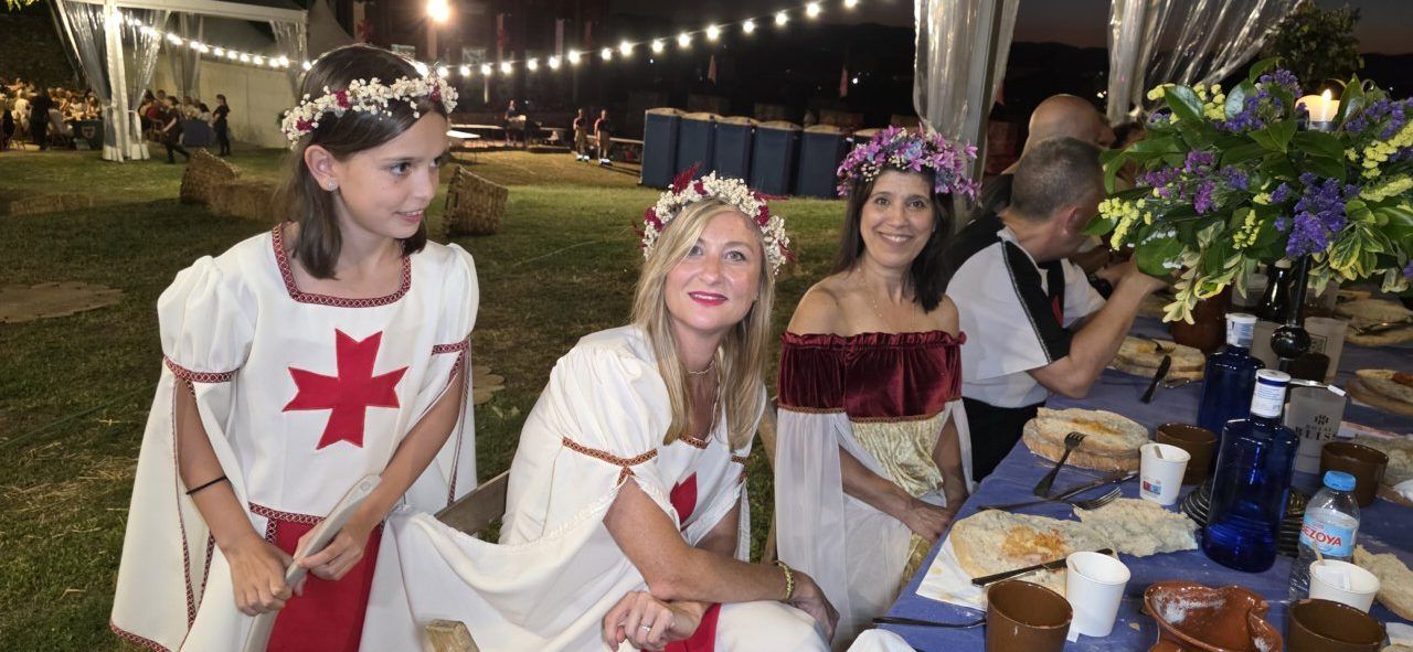 Participantes en la Cena Templaria con vestimenta tradicional y decoración floral