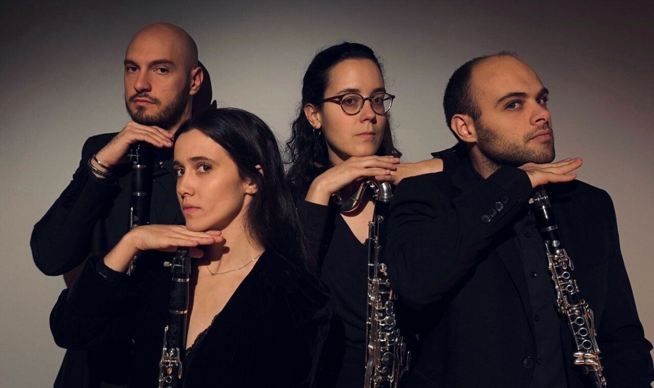 El Cuarteto Nivalis posando con clarinetes en un fondo oscuro.