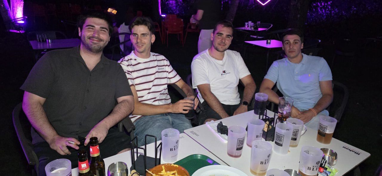 Cuatro amigos sentados en una mesa en una fiesta nocturna