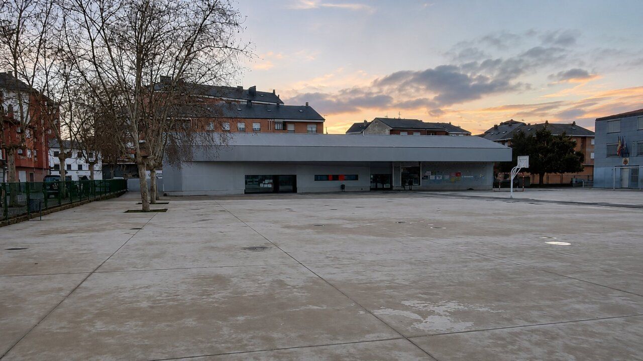 Vista de un colegio en Ponferrada con un patio vacío y edificios alrededor.