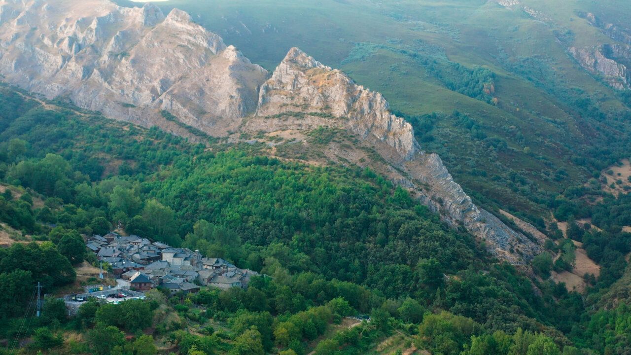 Vista panorámica de un paisaje berciano con montañas y un pueblo.
