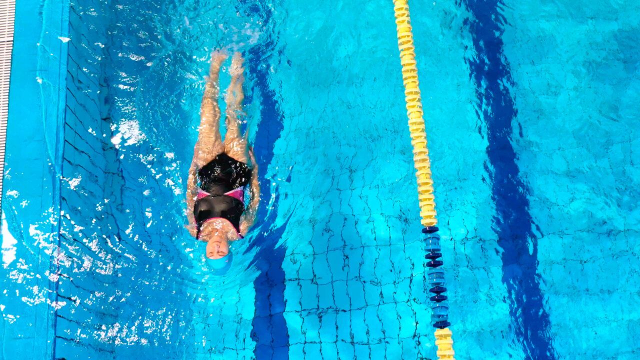 Mujer nadando en una piscina olímpica con agua azul clara